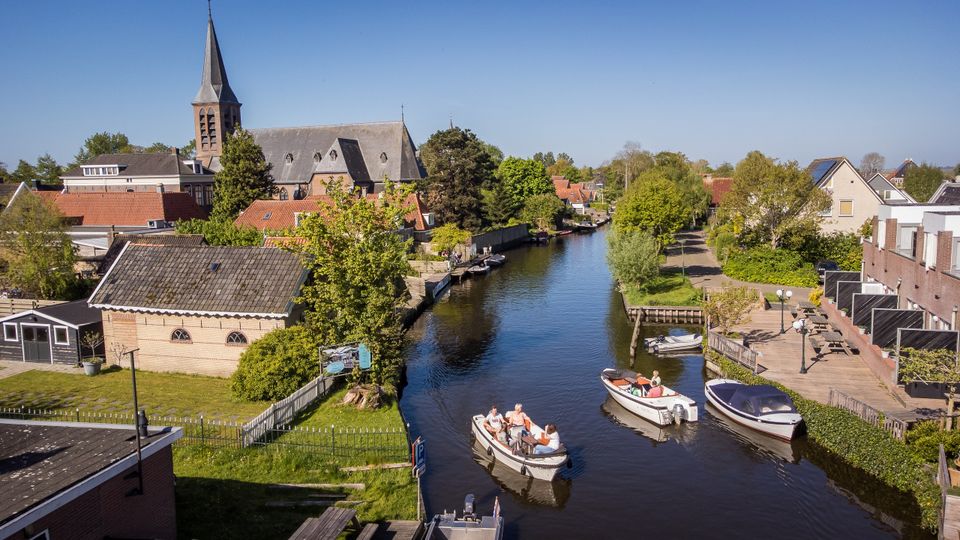 Luftaufnahme von Schaluppen, die durch das Dorf Heeg fahren