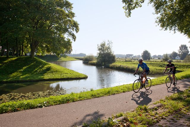 Twee fietsers op mountainbikes fietsen langs vestingwallen Klundert in de zomer