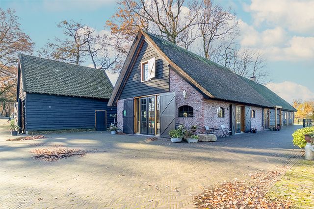 Historische boerderij van De Paardenkamp in Soest, met rieten dak en karakteristieke houten en bakstenen gevels. De landelijke locatie wordt omringd door bomen en past bij een bezoek aan De Paardenkamp op de Utrechtse Heuvelrug.