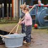 Jongetje en meisje met zwabber en teil met water in de tuin van het Fries Scheepvaart Museum