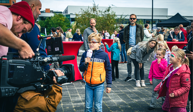 Jong kind met microfoon in de hand doet presentatie terwijl hij wordt gefilmd