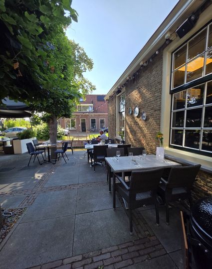 Sfeervol terras van Malou Fine Food & Drinks in Linschoten met tafels onder een boom, ideaal voor lunch, diner of borrel in het Groene Hart