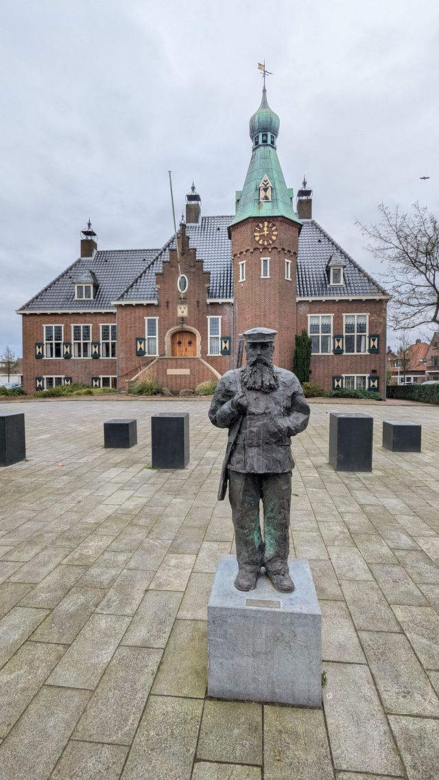 Het karakteristieke gemeentehuis van Woudenberg met daarvoor een standbeeld op het plein. De foto laat het monumentale raadhuis en de historische uitstraling van het dorpscentrum zien.