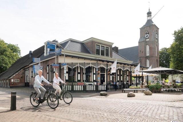 Ruinen - Brinkdorp in Zuidwest-Drenthe. Je ziet twee mensen op de fiets langs de brink fietsen.