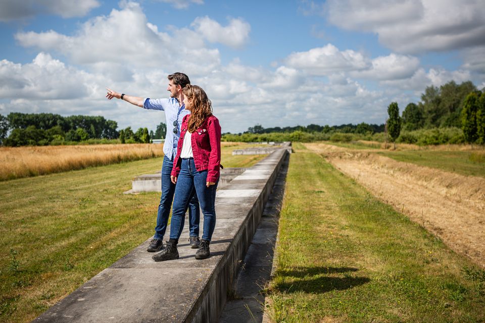 Een man en een vrouw staan op de betonnen rand van Fectio en kijken over het fort.