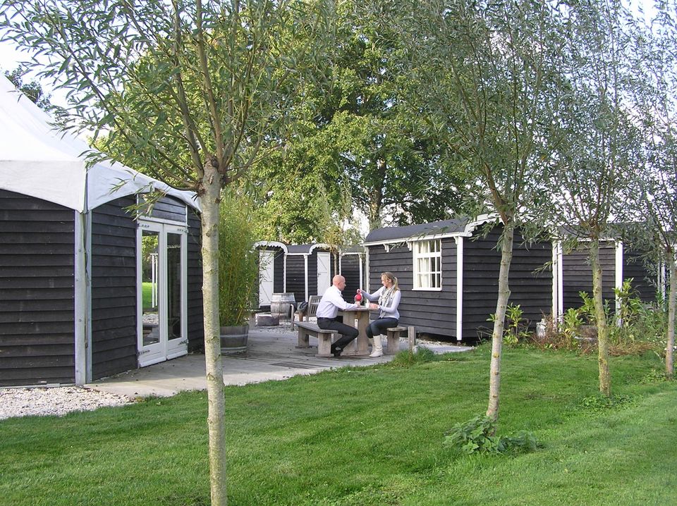 Overzicht van de Veldhuysjes bij Kameryck met een groene buitenruimte waar twee mensen aan een picknicktafel zitten.