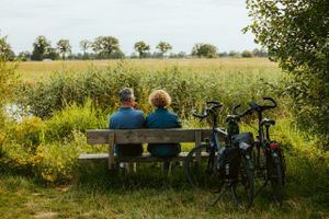 Man en vrouw zitten op het bankje kijkend naar het uitzicht van de natuur in het Land van Peel