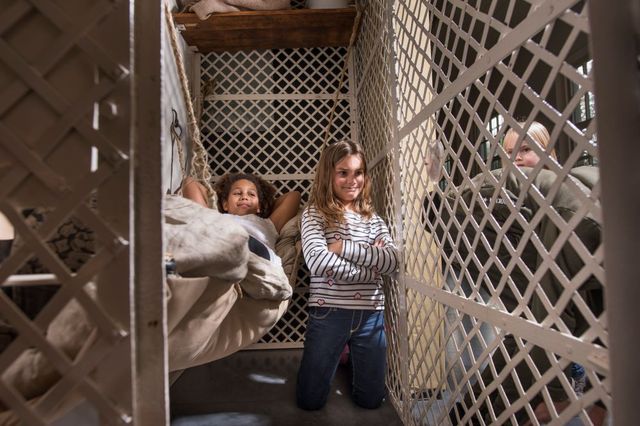 Drie kinderen spelen in een cel in het Gevangenismuseum