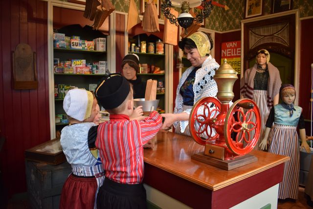 Twee kinderen en een vrouw in klederdracht in Museum Urk