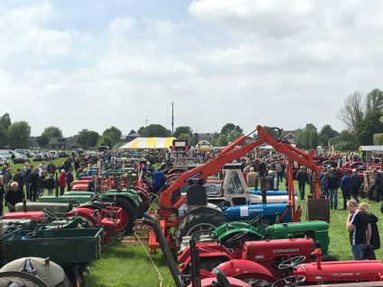 Bezoekers bekijken een groot veld vol oldtimer tractoren tijdens de O.P.A. trekkerdag in Harmelen, met demonstraties en gezellige drukte op het evenemententerrein