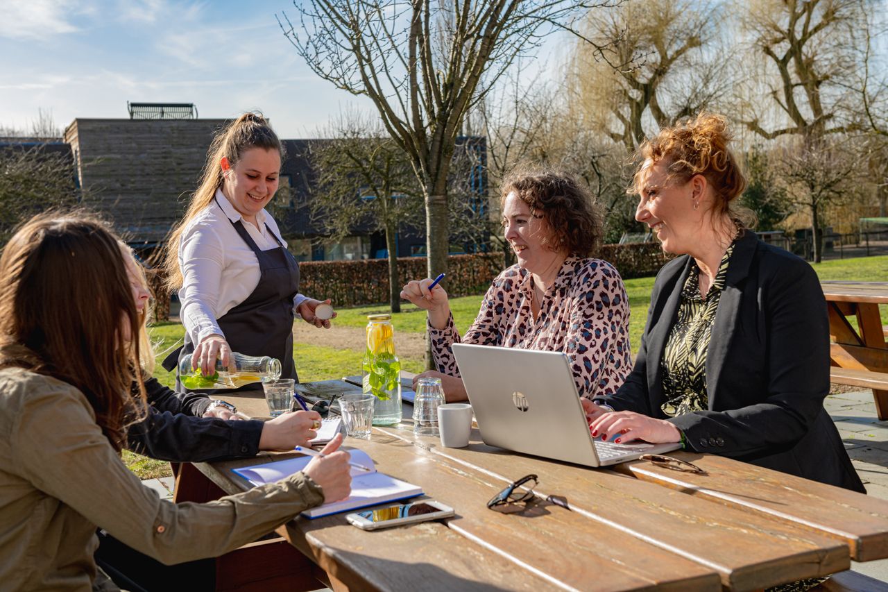 Drie mensen aan tafel tijdens een meetin gop het terras van ZIN