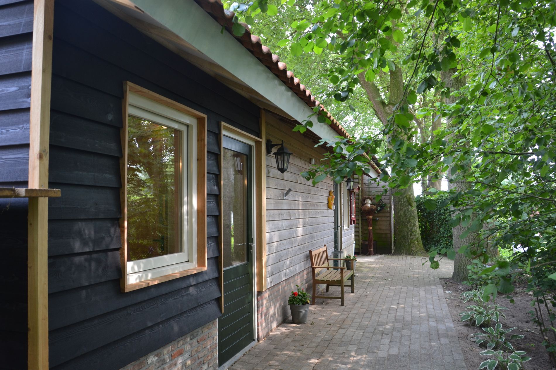 Foto van een houten bijgebouw tussen de bomen.