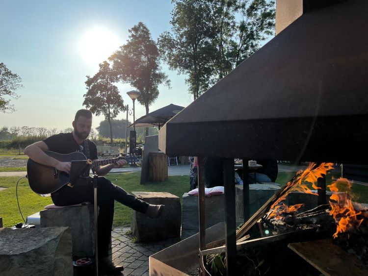 Man op gitaar bij kampvuur