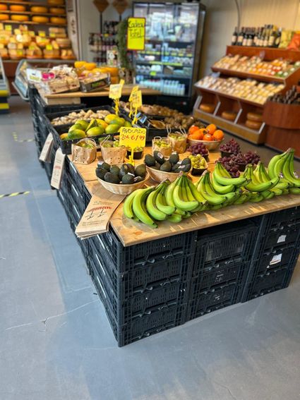 Streekwinkel De Marktwinkel in Woerden, Groene Hart, entree met glazen schuifdeuren en gevel met groen wandpaneel, binnen zichtbaar verse groenten, fruit en lokale producten in de verswinkel.