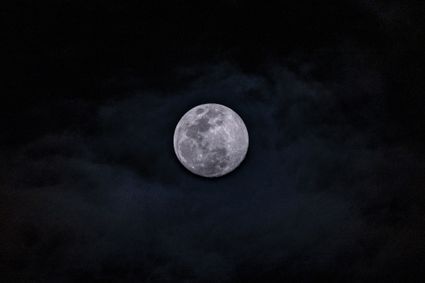 Volle maan aan een donkere hemel met wolken, passend bij de Nacht van de Nacht en de avondwandeling op Landgoed Bredius in Woerden.