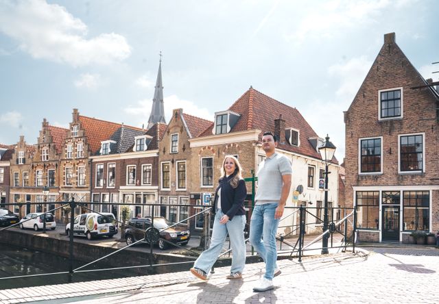 Historische binnenstad Oudewater, Groene Hart, bezoekers wandelen over de brug langs karakteristieke grachtenpanden en monumentale gevels met uitzicht op de kerktoren en het sfeervolle stadscentrum.