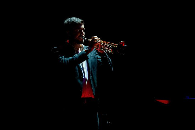 Een trompettist speelt tijdens een liveoptreden op een donker podium. De foto brengt de sfeer van jazzmuziek tot leven en sluit aan bij het jazzconcert van het Noam Bargil Trio in het RIEtheater in Woerden.