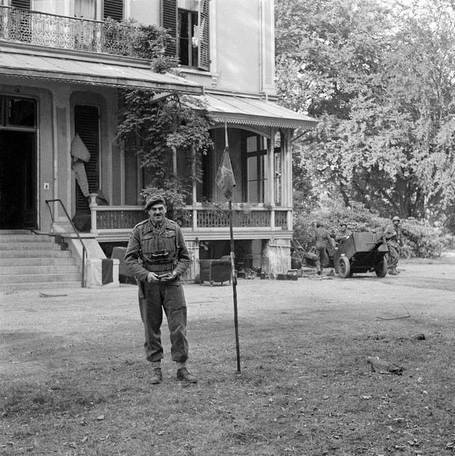Major-general Urquhart in front of the headquarters in Hotel Hartenstein with next to him the pennant of the 1st Airborne Division