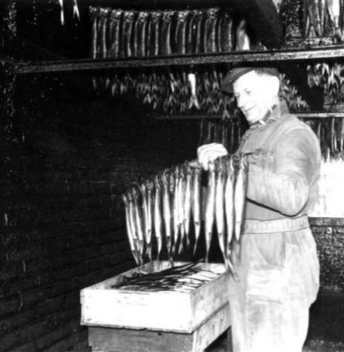 Een zwart-wit foto van een man die vis aan het roken is