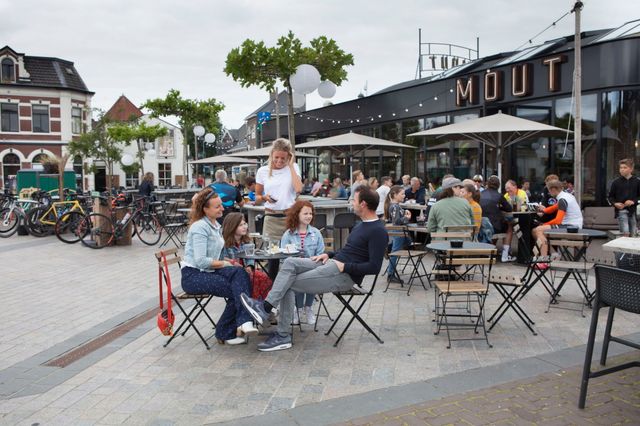 Terras van foodhall MOUT in Hilversum met gezin aan een tafeltje.