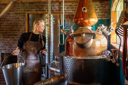 Vrouw aan het werk bij een koperen distilleerketel in Chamberick Distillery, waar ambachtelijke likeuren worden gestookt, onderdeel van Hollandse Ambachten Utrecht Region.