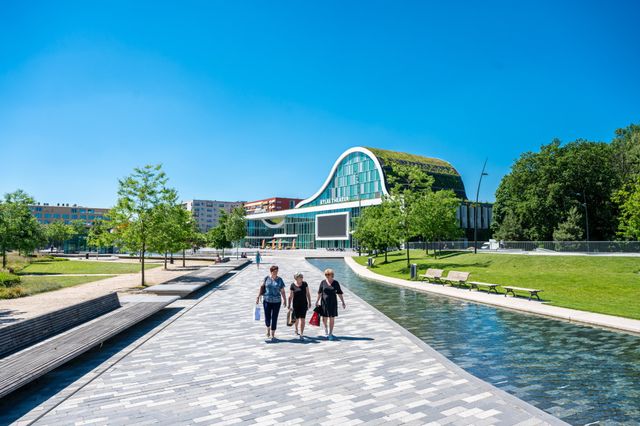 Drie vrouwen lopen tijdens een dagje winkelen met hun aankopen over het plein.