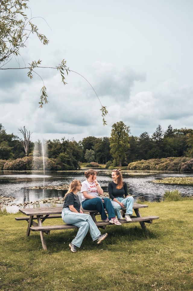 Drie vriendinnen zitten op een bankje voor de vijvers van Paleis Soestdijk