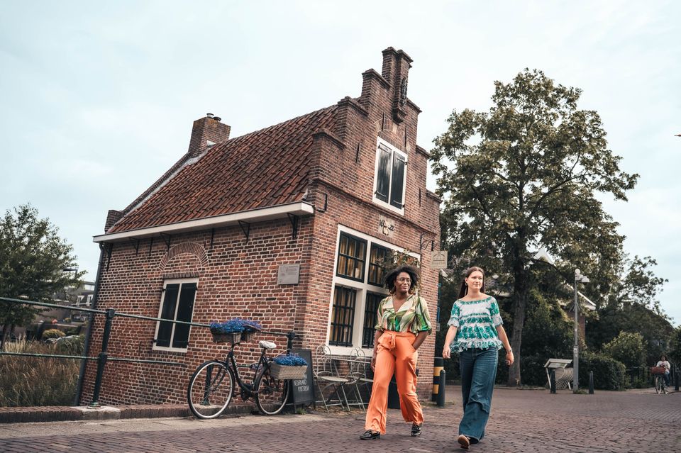 Historisch pand in IJsselstein, Groene Hart, twee vrouwen wandelen door het oude centrum langs een karakteristiek bakstenen gebouw met trapgevel. Fotografie: Studio Chanou.