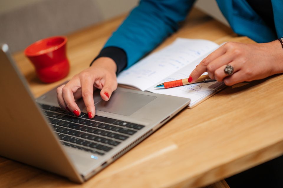 Vrouw zit achter een laptop aan het bureau.