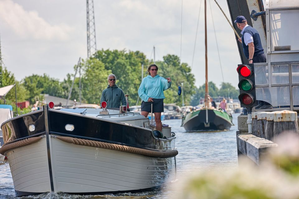 Een motorjacht vaart de openstaande brug bij Delfstrahuizen.
