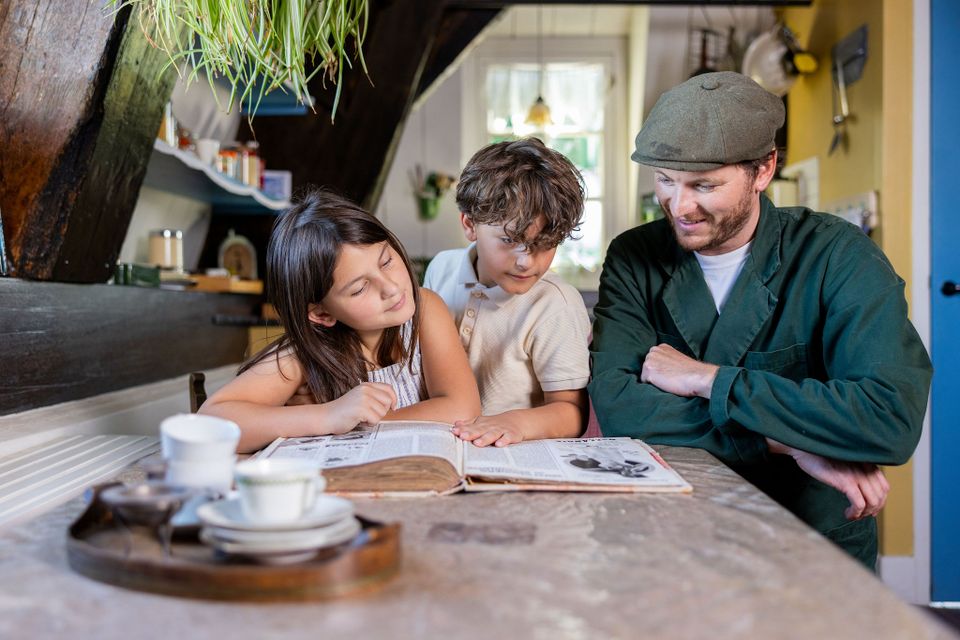 Museummolen Nederwaard, Kinderdijk, Alblasserdam, Zuid-Holland, Groene Hart, historische museummolen waar een molenaar kinderen een oud boek laat bekijken in het authentieke moleninterieur van UNESCO Werelderfgoed Kinderdijk.