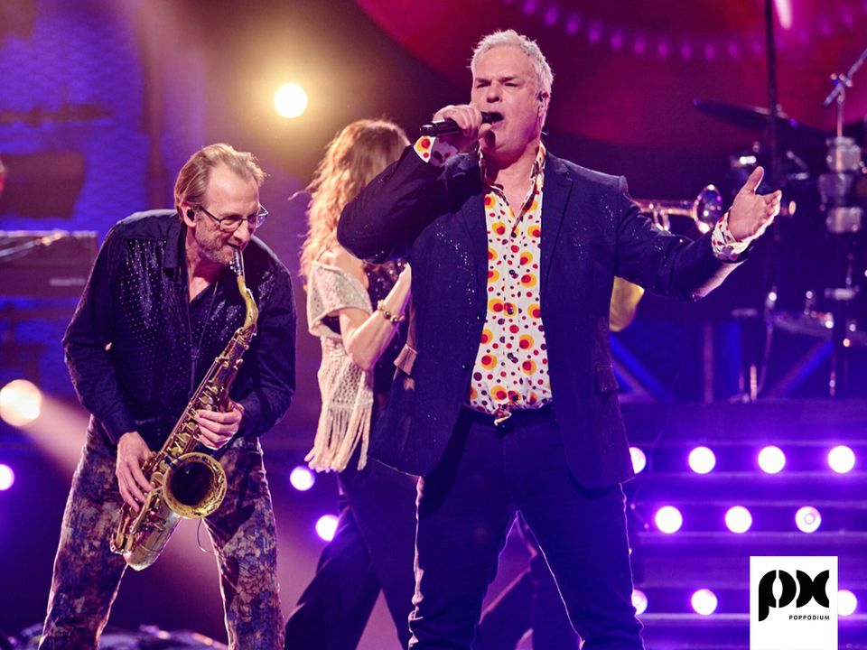 Een band die aan het optreden is: een man zingt, de ander speelt op een saxofoon