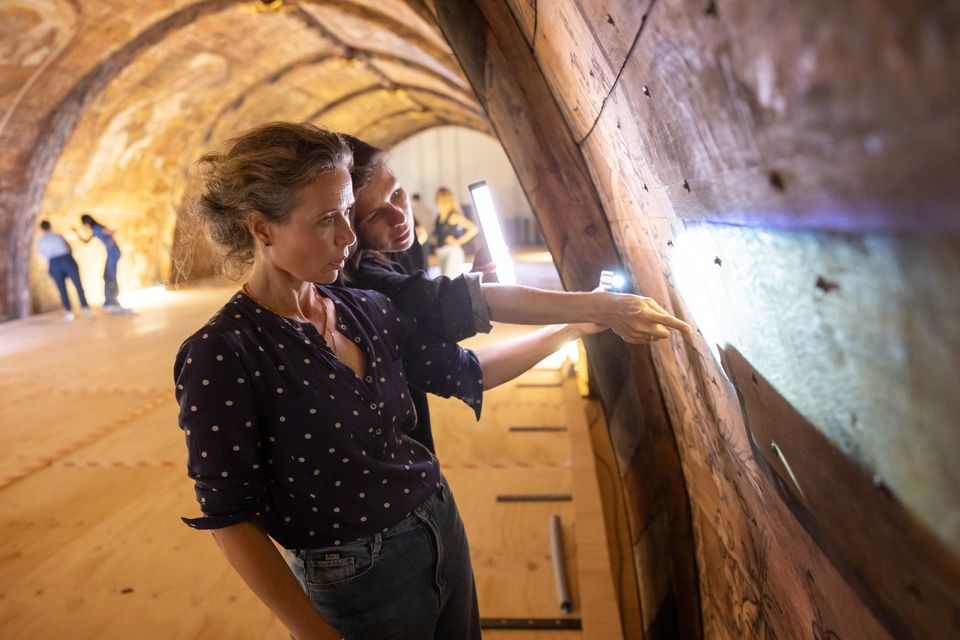 Twee bezoekers bekijken de eeuwenoude schilderingen op het tongewelf van Grote Kerk Naarden.
