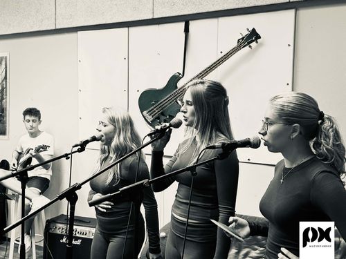 Drie vrouwen zingend voor een microfoon