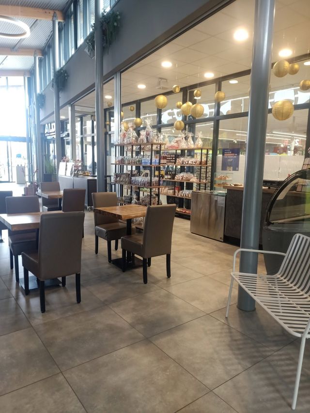 Binnenterras met tafels en stoelen, op de achtergrond schappen met producten en cadeau pakketten.