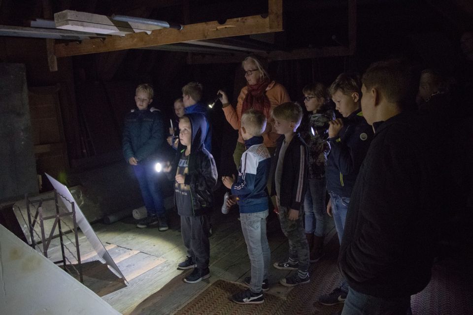 Kinderen zijn samen met een begeleider op zaklampentocht in Kasteel Amerongen