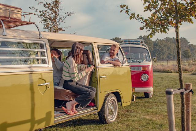 Jong volwassenen zitten in een camperbusje aan een kopje koffie in de ochtend.
