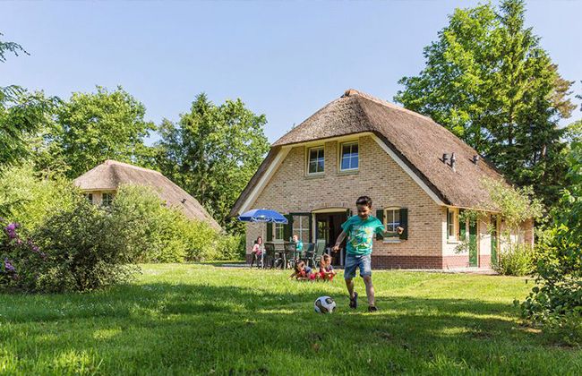 Ein Junge spielt Fußball vor dem Häuschen.