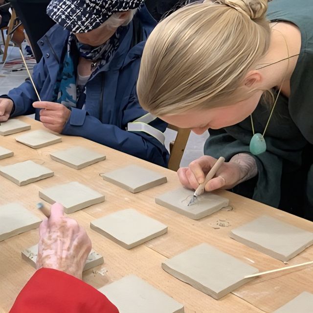 Bezoekers maken kleitegeltjes