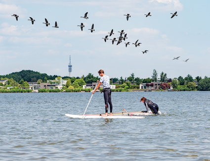 Twee personen op water aan het suppen.