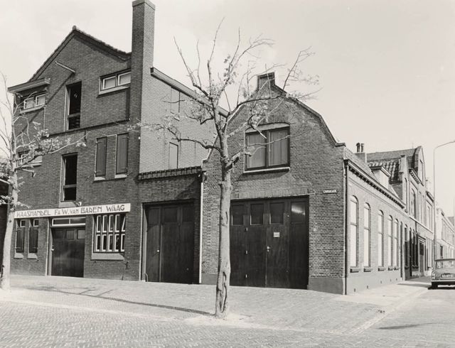 Zwart-witfoto van de buitenkant van Het Kaaspakhuis in Woerden aan de Emmakade met de naam Kaashandel Fa. W. van Barem.