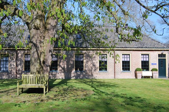 Een monumentale woning met een grote boom ervoor.