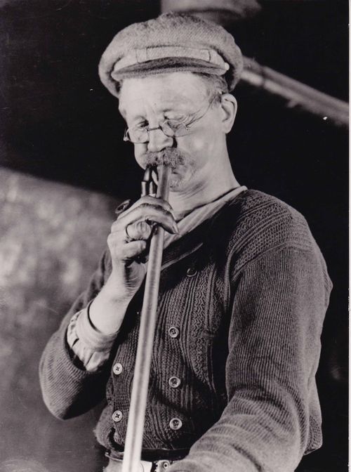 Een historische foto van een man die glas aan het blazen is.