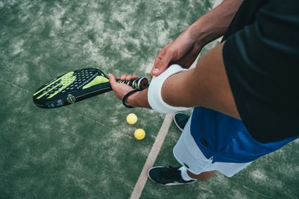 Padel - close-up van handen met een racket en 2 padelballen