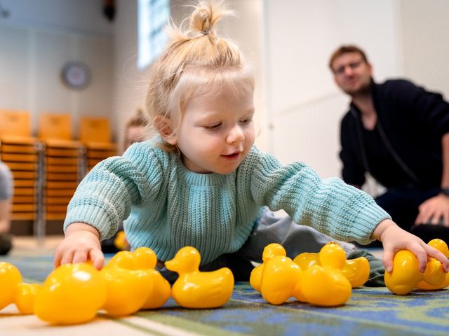 Kinderfestival met speelse activiteit, peuter die speelt met gele badeendjes in Het Klooster, Woerden, Groene Hart, rustig en interactief speelmoment tijdens een cultureel programma voor jonge kinderen.