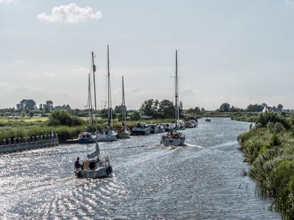 Zeilboten die aan de kant staan van de oever en zeilboten die langs varen in Langweer.