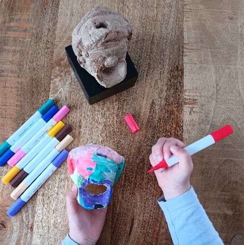 Archeologische kinderworkshop in Woerden, Groene Hart. Kind beschildert een replica van een Romeinse vondst tijdens een creatieve activiteit over archeologie, de Limes en de Romeinse geschiedenis van Woerden.