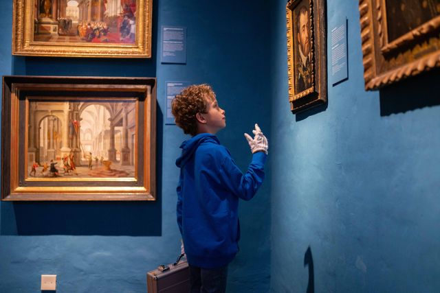 Een jongen met een blauwe trui die de schilderijen in het Prinsenhof Museum in Delft bekijkt