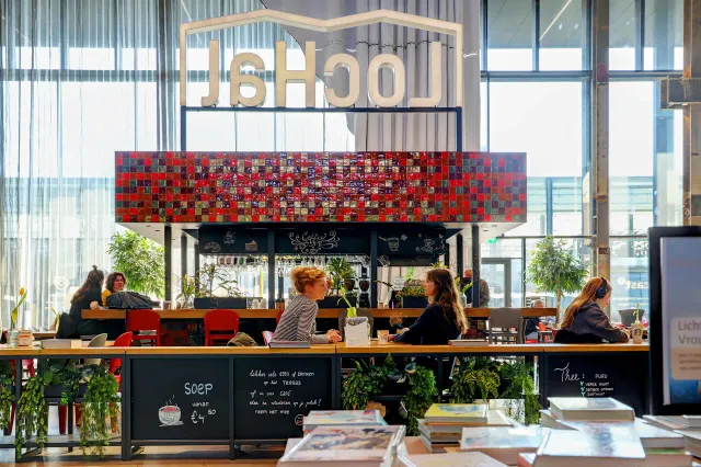Twee bezoekes aan een tafeltje in het cafe van de LocHal met de grotere glazen raampartij op de achtergrond