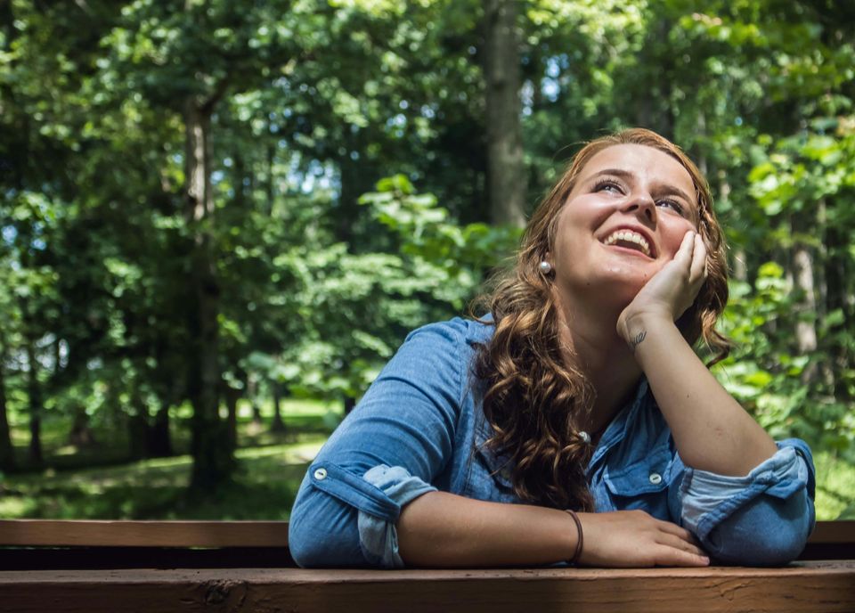 Vrouw leunt op vuist en kijkt lachend naar boven